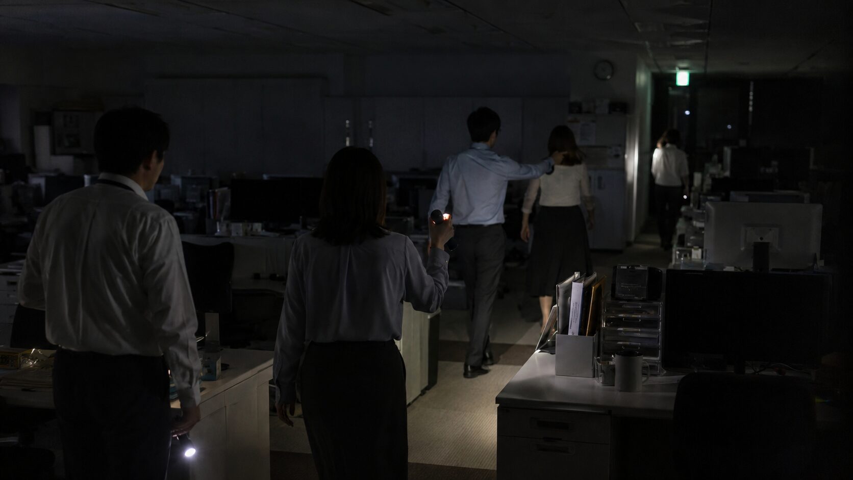 災害時の職場で社員が状況を確認しながら行動しているイメージ